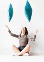 woman sitting on the floor throwing pillows into the air