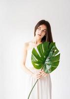 Happy beautiful woman in cozy clothes holding a green monstera leaf photo