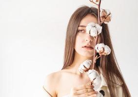 Beautiful woman in cozy clothes holding branch of cotton flowers photo