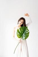 Happy beautiful woman in cozy clothes holding a green monstera leaf photo