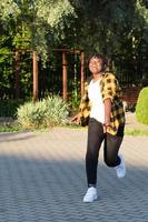 a happy African American woman in the park makes a jump in the summer photo