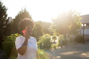 happy African American woman with a phone on the street in the summer photo