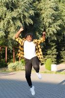 una mujer afroamericana feliz en el parque da un salto en el verano foto