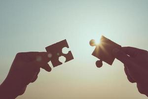 Silhouette of closeup hands holding connection jigsaw puzzle photo
