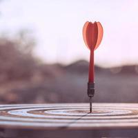 Red dart arrow hitting target centre dartboard photo