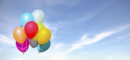 Balloons flying on blue sky background photo