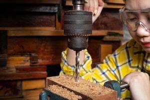 las mujeres de pie es artesanía trabajando madera de taladro