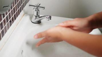 closeup mãos de mulher jovem usando sabonete e lavando as mãos sob a torneira de água, mulher lava as palmas com bolhas brancas na pia do banheiro do hotel para higiene protegê-la de covid-19 video