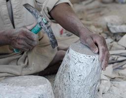 hands of a male Egyptian sculptor while working with a stone alabaster