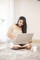 Bastante joven indio usando la computadora portátil en casa foto