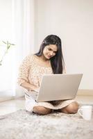 Bastante joven indio usando la computadora portátil en casa foto