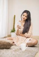 Attractive young Indian woman relaxing with mobile at home. photo