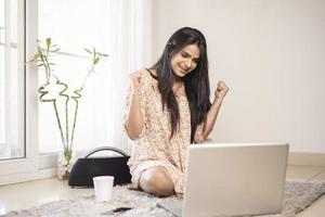Exited young Indian woman with laptop at home. photo
