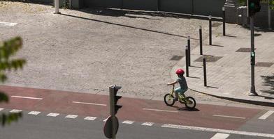 A boy pedals on his bicycle in the bicycle lane in Madrid, Spain