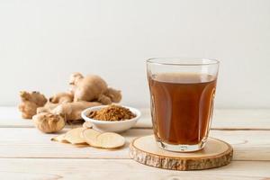 Hot and sweet ginger juice glass with ginger roots - Healthy drink style photo