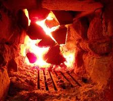 red fire from slice wood, dark grey black coals inside metal brazier photo