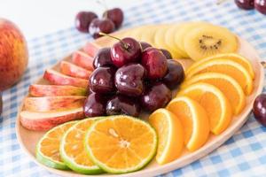 Mixed sliced fruit in wood bowl photo