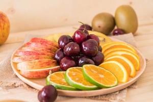 Mixed sliced fruit in wood bowl photo