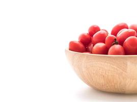 Tomates frescos en un tazón de madera sobre fondo blanco.