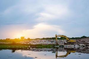 A yellow backhoe is lifting garbage at waste separation plant photo