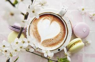 Coffee with a heart-shaped pattern and sweet macaroons desserts photo