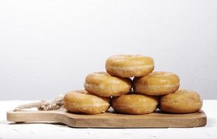 Mucho donut en una tabla de madera sobre fondo blanco. foto