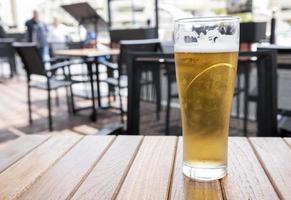 Vaso de cerveza fría con espuma sobre una mesa de madera foto