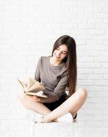 Woman sitting on the chair with legs crossed reading a book