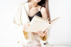 woman in comfortable home clothes reading a book sitting on the floor photo