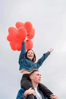 young loving couple with red balloons embracing outdoors having fun