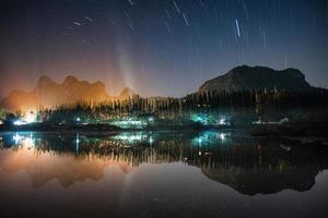 Hermosos senderos de estrellas sobre la montaña con reflejo en el lago foto