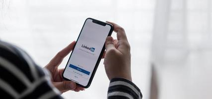 chiang mai, tailandia 2021: una mujer sostiene el iphone xs de apple con la aplicación de linkedin en la pantalla. foto