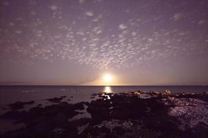 Moonlight and starry sky illuminating the ocean on the Big Island, photo