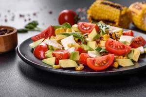 Delicious fresh salad with tomatoes, avocado, cheese and grilled corn photo