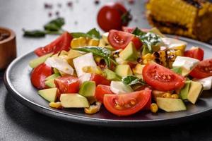 Delicious fresh salad with tomatoes, avocado, cheese and grilled corn photo