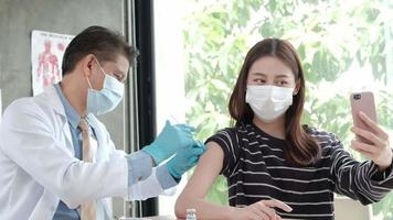 Asian woman taking a selfie while a doctor is vaccinating. video