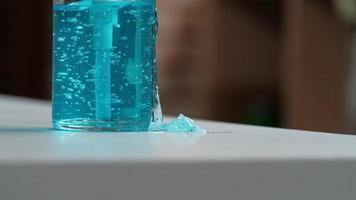 primer plano, botella de alcohol presionada, gota de gel azul claro y transparente sobre la mesa blanca. El lavado de manos es una nueva norma para prevenir la infección por coronavirus covid-19, bacterias y enfermedades. video