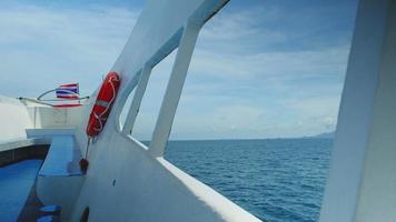 uitzicht door het raam op de boeg van de veerboot vervoert toeristen uit baaien in thailand op vakantie, prachtig landschap, blauwe zee, bewolkte hemel op zonnige dag. en op het dek van de boot ligt een reddingsboei. video