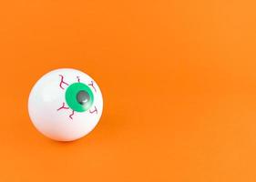 One scary eyeball on an orange background with copy space. photo