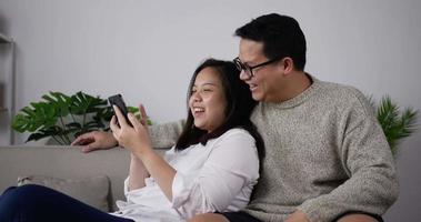 couple heureux utilisant un smartphone jouer à un jeu mobile video