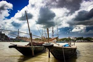 Barco de pesca tradicional en la orilla del río bajo el cielo nublado foto