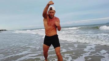 Hombre haciendo ejercicio matutino en la playa con boxeo video