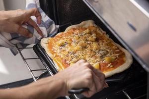 woman hands taking pizza out of the oven