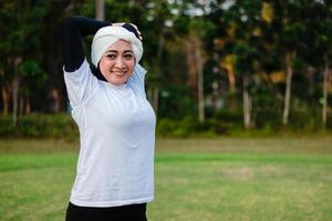 Pleasant woman in hijab and sportswear doing yoga and stretching. photo