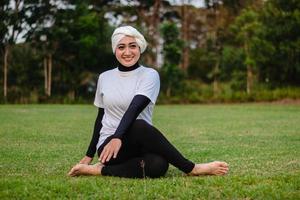 mujer agradable en hijab y ropa deportiva haciendo yoga y estiramiento. foto