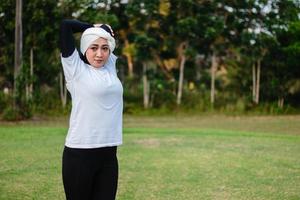 Pleasant woman in hijab and sportswear doing yoga and stretching. photo