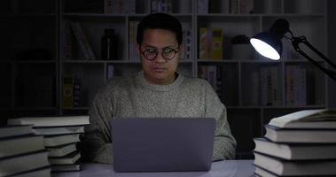 jovem trabalhando em um laptop em uma sala mal iluminada video