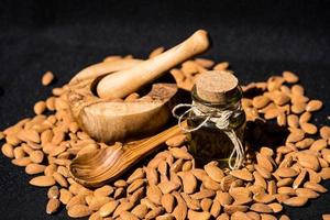 un montón de almendras y un vaso con aceite de almendras foto