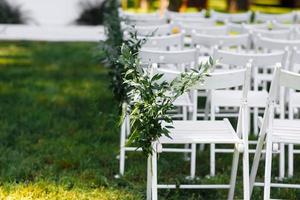 Decorated white chairs at a wedding ceremony photo