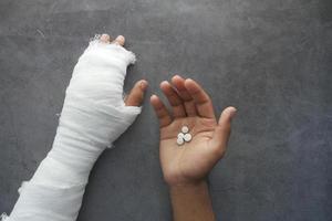 injured painful hand with bandage and medical pills on hand photo
